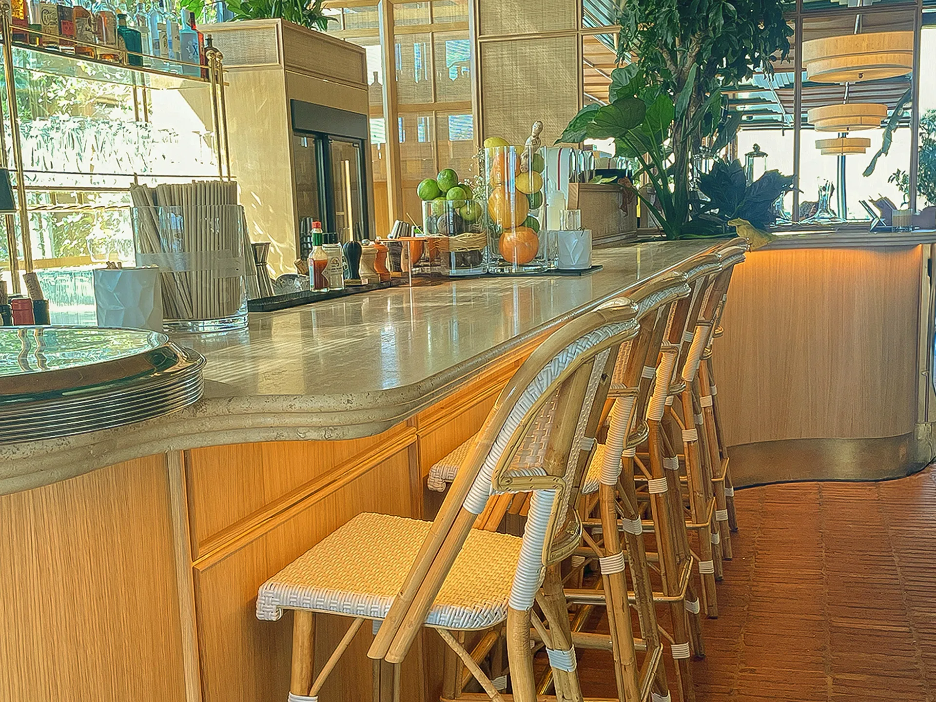 Bar sur mesure avec comptoir en pierre naturelle, assises en rotin et ambiance végétalisée